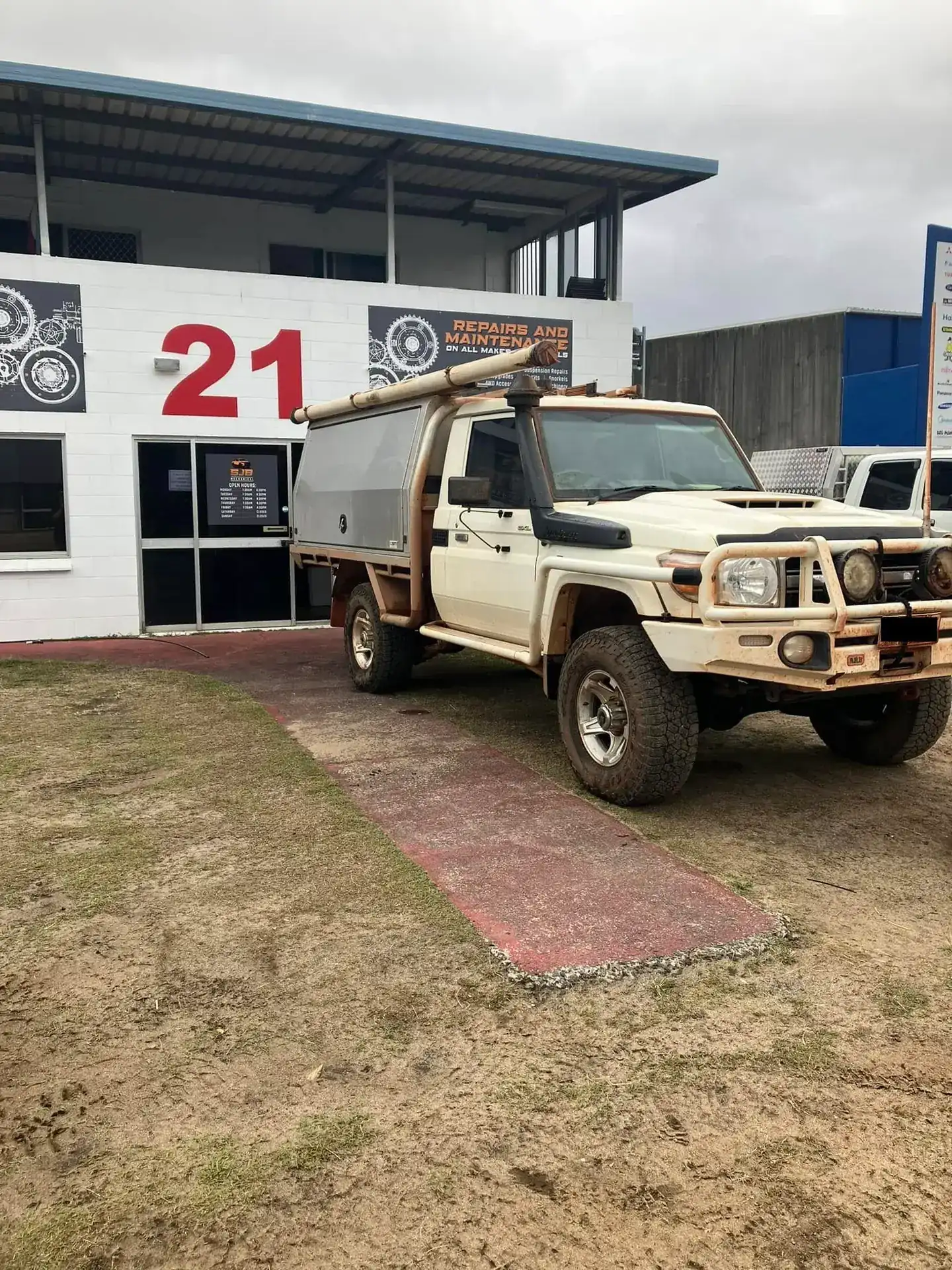 The SJB Mechanical workshop building on an overcast day, with a well-used tray-back 4WD parked outside