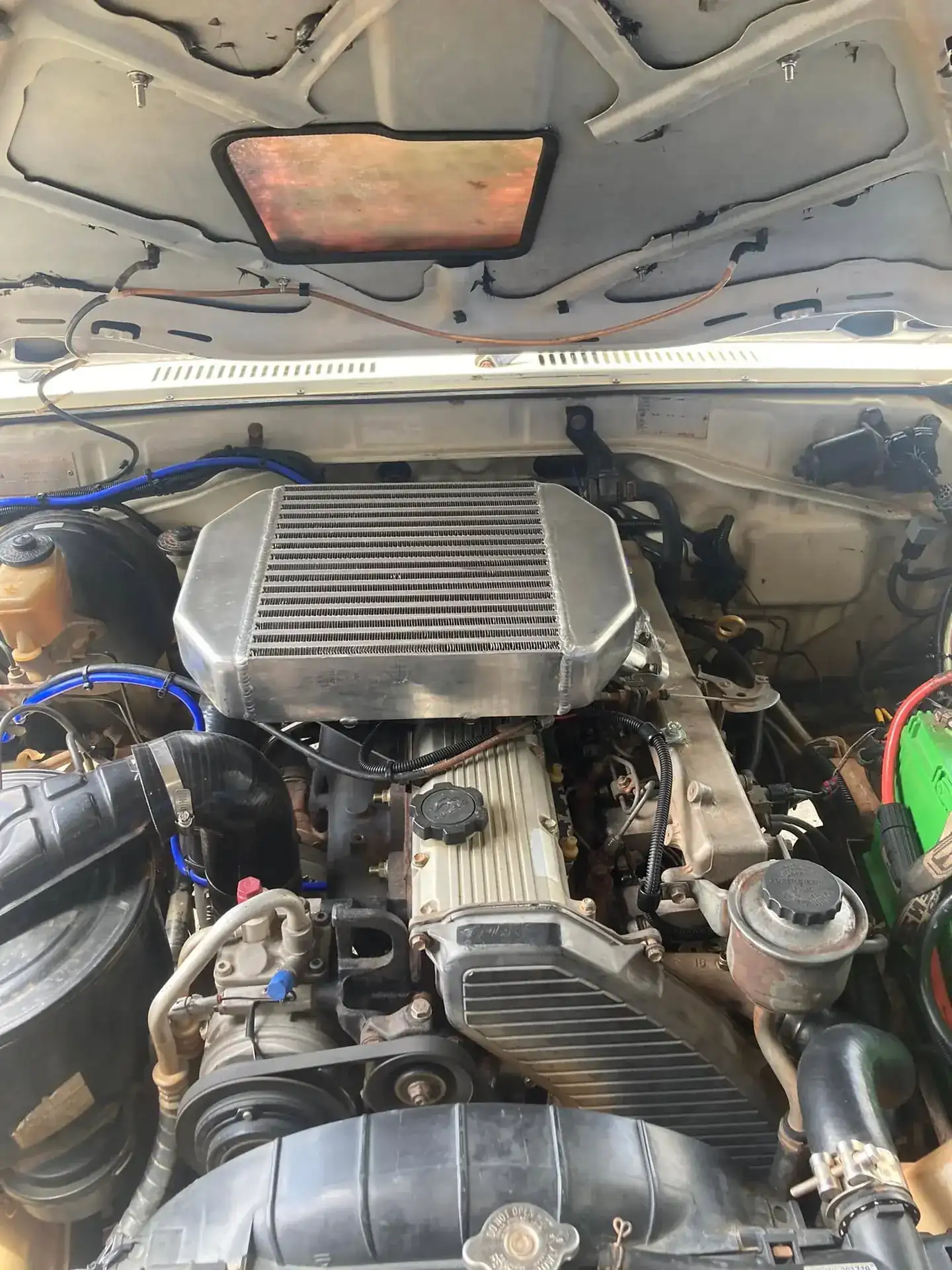 A diesel engine bay with an aftermarket intercooler and piping installed