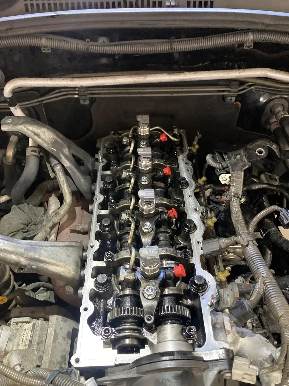 A close-up of an engine's cylinder head with the valve cover removed and injectors exposed