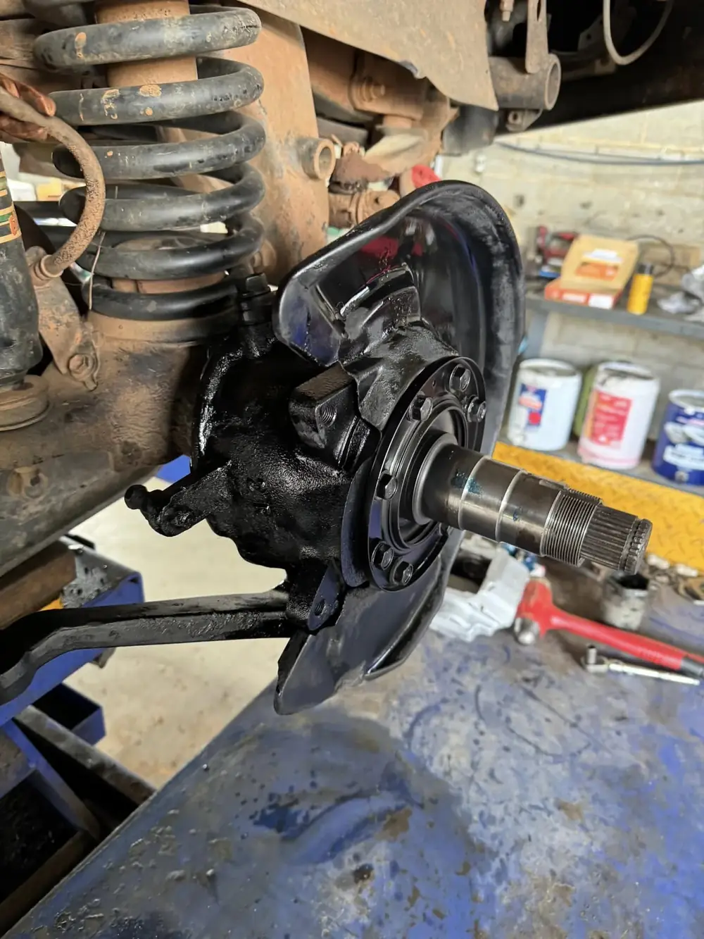 A freshly refurbished steering knuckle and wheel hub with the coil spring visible above
